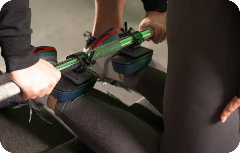 Sports coach using two K-push handheld dynamometer to measure an athlete's leg strength