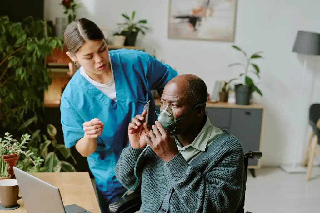 A female nurse assisting a senior male patient wearing an oxygen mask in a care setting