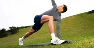 Les 4 piliers du mouvement : mobilité, stabilité, force et mouvement fonctionnel 1 Man performing a deep lunge with a thoracic rotation stretch on a mat outdoors, illustrating a mobility exercise