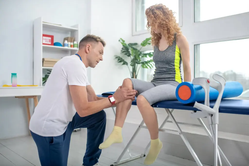Physical therapist manually assessing a female patient's knee during a rehabilitation session after an ACL injury