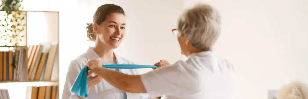 Physical therapist guiding a senior patient during an elastic band exercise to demonstrate Evidence-Based Practice in physiotherapy