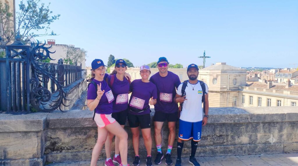 Montpellier Reine 2026 : les collaborateurs Kinvent mobilisés pour une cause qui nous rassemble 1 L'équipe de collaborateurs Kinvent posant tout sourire en tenue de course lors de l'événement solidaire Montpellier Reine 2026, avec les toits de la ville en arrière-plan depuis la promenade du Peyrou