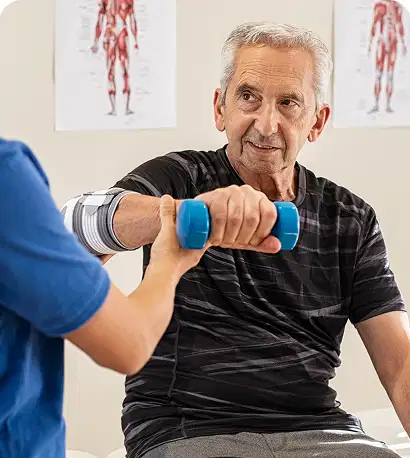 Fisioterapeuta 45 Un hombre mayor con el codo vendado guiado por un fisioterapeuta mientras realiza un ejercicio de rotación de antebrazo con una pequeña mancuerna azul en una clínica.