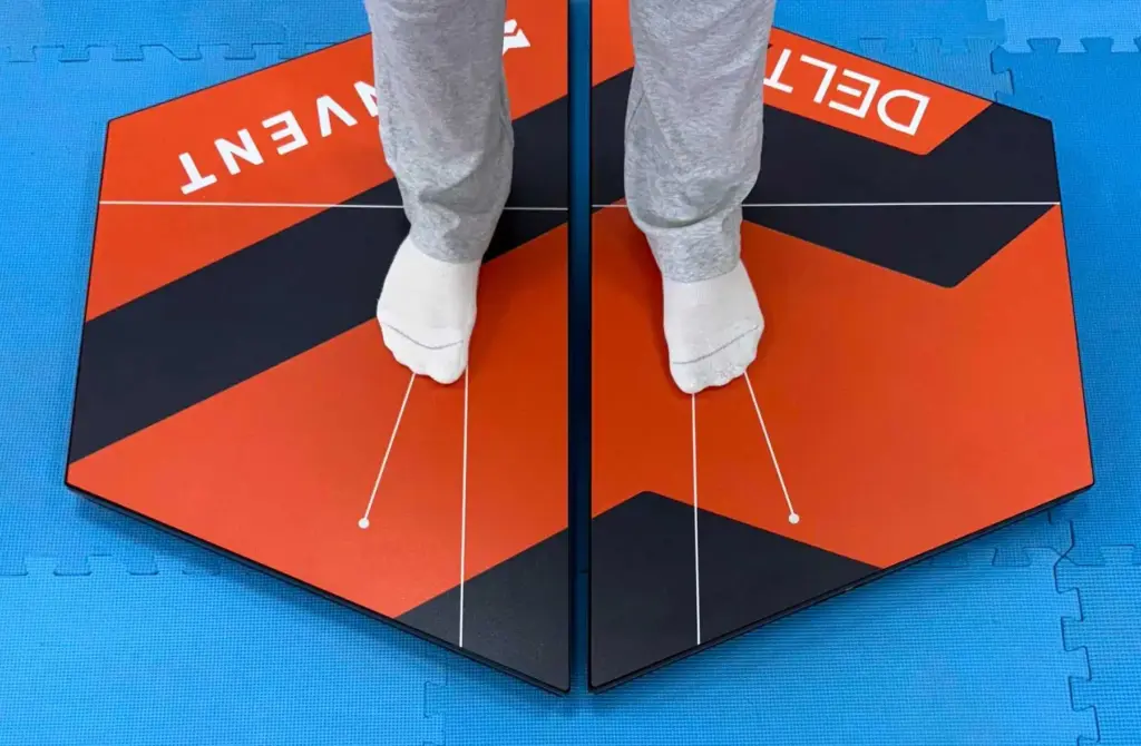 A close-up, top-down view of a patient's feet in socks standing on Kinvent K-Deltas XL extra-large connected force plates, designed for precise balance and biomechanical posture analysis