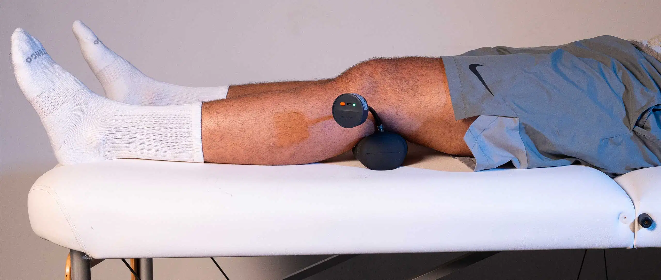 K-Bubble 47 A patient lying down on a treatment table, squeezing a K-Bubble pressure sensor between their knees to evaluate inner leg strength