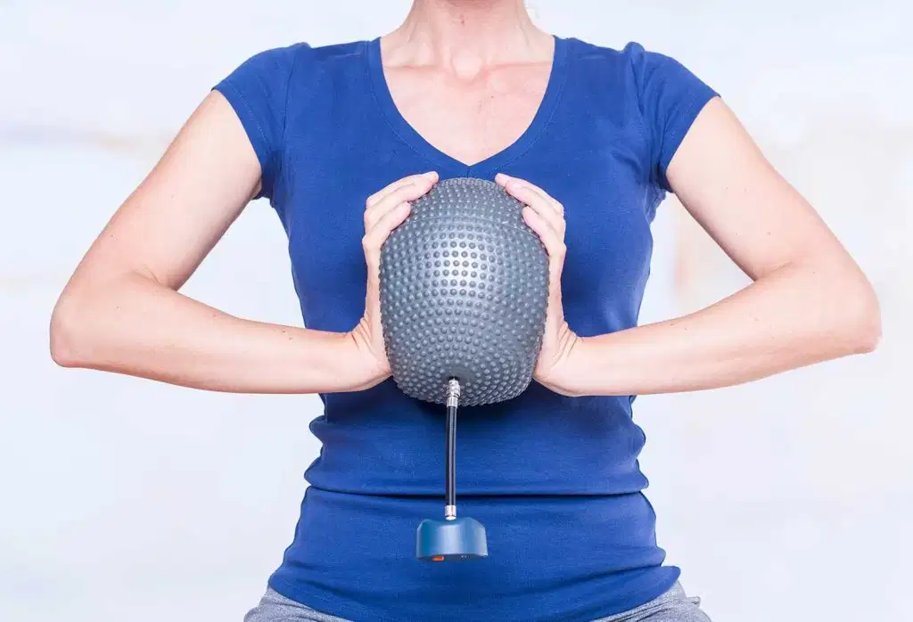 K-Bubble 42 A front view of a woman in a blue t-shirt pressing a grey textured K-Bubble pressure balloon between her hands to evaluate upper body strength